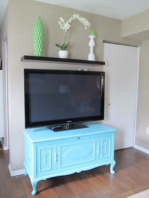 a bright aqua cedar chest with legs used as a tv console in a modern living room