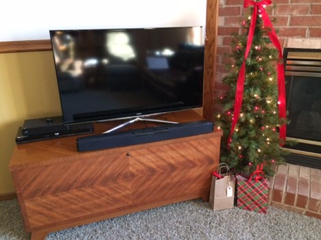 a wooden cedar chest creatively used as a tv console in a christmas decorated living room