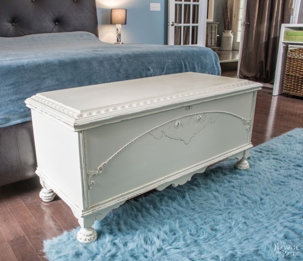 white refurbished cedar chest sitting at the end of the bed in a blue accented room